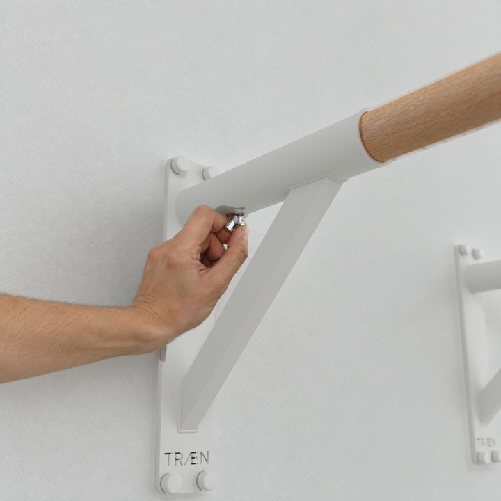 Eine Hand zieht die Flügelschraube unter dem Griff von Hand nach.