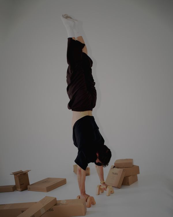 Der Gründer im Handstand auf den Handstandgriffen LG1, um ihn herum TRÆN-Kartons.