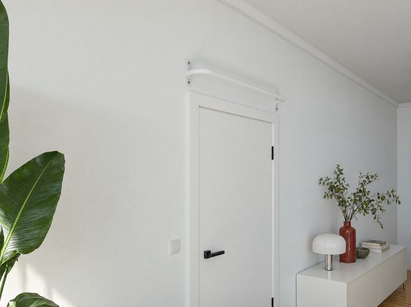 KS1 Wand-Klimmzugstange in Weiß über einer weißen Zimmertür, daneben ein Sideboard mit Lampe.